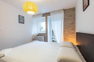 1 dormitorio con cama y ventana grande en Le 05-GregIMMO-Appart'Hôtel, en Montbéliard