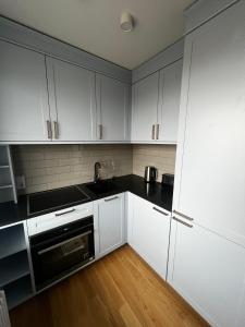 Una cocina con gabinetes blancos y encimeras negras. en Sunrise Lauku Apartments, en Liepāja