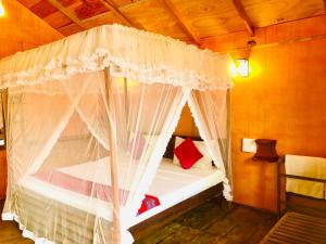 Sungreen Cottage Sigiriya في سيجيريا: غرفة نوم مع سرير مظلة مع ستائر بيضاء