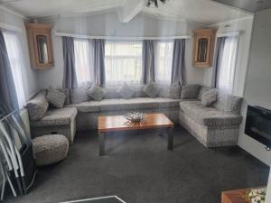 a living room with a couch and a table at S295 3 BED DELUXE PET FRIENDLY CARAVAN in Chapel Saint Leonards