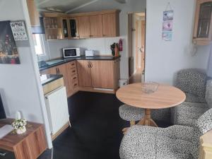 a small kitchen with a table in a small room at S295 3 BED DELUXE PET FRIENDLY CARAVAN in Chapel Saint Leonards