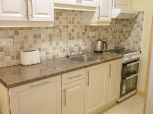 uma cozinha com armários brancos e um lavatório em Glebe House em Ballinrobe