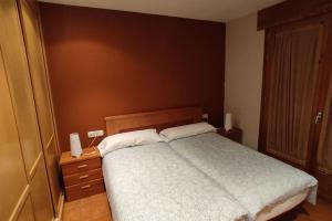 1 dormitorio con 1 cama con cabecero de madera y mesita de noche en Pirineos como en casa, en Bielsa