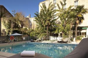 a large swimming pool with palm trees and a building at Hôtel Oceania Le Métropole in Montpellier