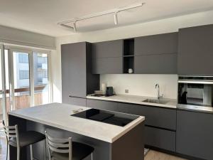 uma cozinha com armários pretos e uma ilha de cozinha com cadeiras em Apartment Regina Luxury Lugano em Lugano