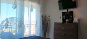 a bedroom with a window and a dresser with a television at Las Delicias ROSES in Roses