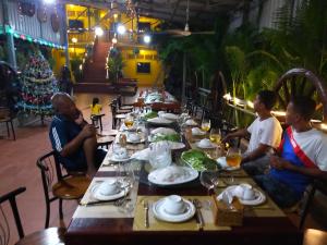 un grupo de personas sentadas en una mesa larga con comida en Phalla Riverside en Kampong Cham