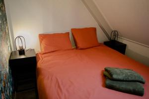 ein Bett mit orangefarbenen Kissen und grünen Handtüchern darauf in der Unterkunft Ruim en landelijk appartement in Wolphaartsdijk