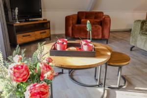 ein Wohnzimmer mit einem Couchtisch mit Tassen und Blumen in der Unterkunft Ruim en landelijk appartement in Wolphaartsdijk