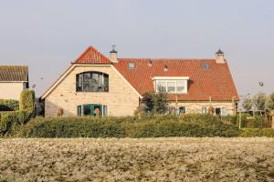 ein großes Haus mit rotem Dach in der Unterkunft Ruim en landelijk appartement in Wolphaartsdijk
