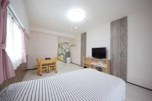 a bedroom with a bed and a desk and a television at STAY IN SUMUKA Kokusai Street in Naha