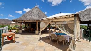 eine Terrasse mit Tischen und Stühlen unter Sonnenschirmen in der Unterkunft Manyatta Camp in Voi