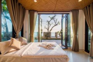 1 dormitorio con cama grande y ventana grande en De' sea Stay PoolVilla @Pranburi ปราณบุรี, en Ban Pak Nam Pran