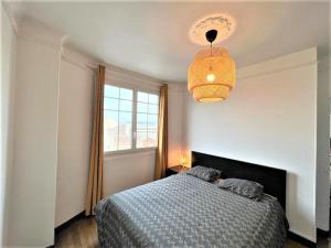 a bedroom with a bed and a window and a chandelier at SUPERBE APPARTEMENT 2 PIECES A 200 METRES GARE in Melun
