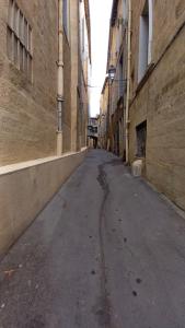 an empty alley between two buildings in an old city at Ambre...La perle rare in Montpellier