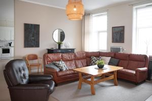a living room with a brown leather couch and a table at Vandrarhemmet Vindarnas Hus in Örnsköldsvik