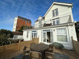 a white house with a wooden table and chairs at Southover Beach in Woolacombe