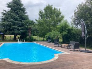 einen blauen Pool mit einer Terrasse, Stühlen und Bäumen in der Unterkunft Cottage proche circuit 24 Heures Le Mans proche de Paris Jeux olympiques autoroute à 5km in La Chapelle-Saint-Rémy