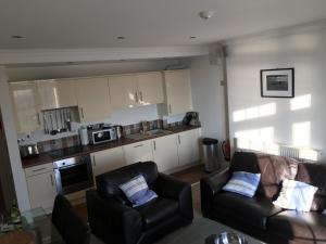 a living room with two couches and a kitchen at Southover Beach in Woolacombe