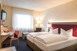 ein Hotelzimmer mit einem großen Bett und einem Schreibtisch in der Unterkunft Hotel Vorfelder in Walldorf