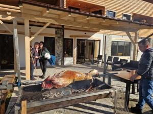 a chicken being cooked on a grill with two people at CASA DE VACANTA CLARA MARIA in Comarnic