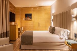 バルセロナにあるHotel Sansi Barcelonaのベッドとダイニングルームが備わるホテルルームです。