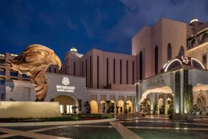 um grande edifício com uma estátua de peixe em frente em The St. Regis Marsa Arabia Island, The Pearl Qatar em Doha