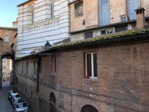 a brick building with cars parked on a street at Alla Scala 1746 in Siena