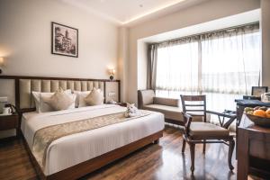 a hotel room with a large bed and a chair at Amritara Sadka Amritsar in Amritsar