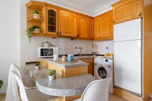 uma cozinha com armários de madeira e um frigorífico branco em Alea Rentals - Turquesa em La Pineda
