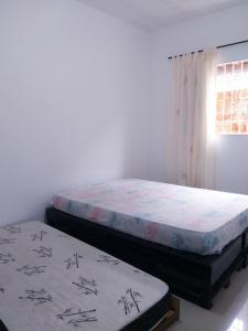 2 aparte bedden in een kamer met een raam bij Casa Cibratel 2 in Itanhaém
