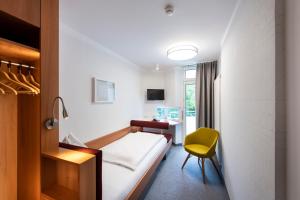 ザルツブルクにあるホテル セント ヴァージル ザルツブルクのベッド、デスク、椅子が備わる客室です。