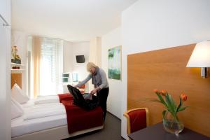 kobieta stojąca w pokoju hotelowym z laptopem w obiekcie Hotel St. Virgil Salzburg w mieście Salzburg +20 zdjęć