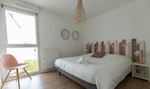 1 dormitorio blanco con 1 cama y 1 silla en Riviera - T3 avec piscine partagée et parking proche plage Arzon, en Arzon