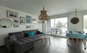 sala de estar con sofá y reloj en la pared en Riviera - T3 avec piscine partagée et parking proche plage Arzon, en Arzon