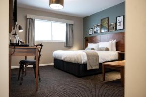 um quarto de hotel com uma cama, uma secretária e uma mesa em The Springfield Inn by Innkeeper's Collection em Lowdham