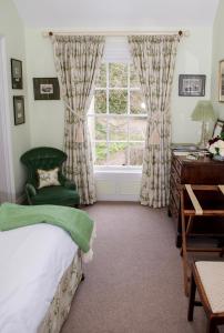 a bedroom with a bed and a desk and a window at Ballymote Country House in Downpatrick