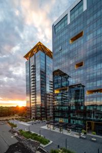 a tall glass building with a sunset in the background at ONE Tower Apartments in Bucharest