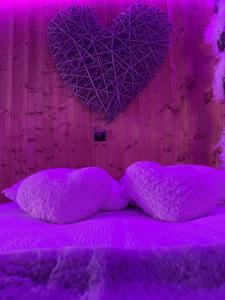 - un lit violet avec des oreillers violets et un mur de cœur dans l'établissement Aux 67 nuances - Spa, à Châtenois
