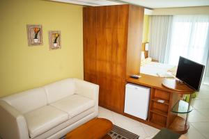 a living room with a couch and a desk with a computer at Gloria Garden Suites in Macaé