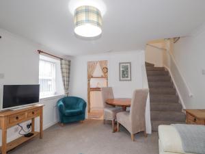 a living room with a table and a staircase at Meredith Cottage in Banff