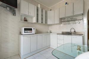 a kitchen with white cabinets and a sink and a microwave at Nadezhda Apartments in Samal in Almaty