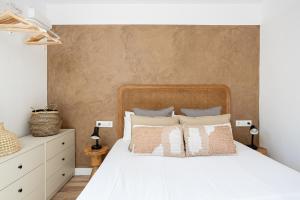 Walk To Las Ramblas Sun-filled&cozy في برشلونة: غرفة نوم بسرير ابيض عليها مخدات