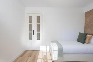 a white bedroom with a bed and a door at Walk To Las Ramblas Sun-filled&cozy in Barcelona