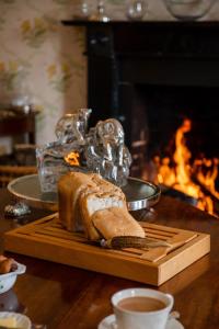 a loaf of bread on a cutting board next to a fireplace at Ballymote Country House in Downpatrick