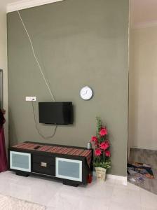 a living room with a tv on a wall with flowers at Homestay Cikgu Fatiah in Kota Bharu