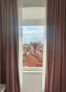 a window with curtains and a view of a city at Ida Old Town Rooms in Dubrovnik