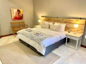 een slaapkamer met een groot bed met een houten hoofdeinde bij Selah Guest Cottages Self-catering Farmstay Accommodation in Nelspruit +142 foto's