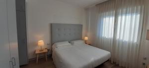 biała sypialnia z łóżkiem i oknem w obiekcie Delta Hotel Apartments w mieście San Donato Milanese