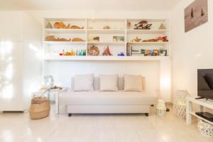 a white living room with a white couch and shelves at Follow the Sun in Cagliari